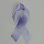Close-up of a purple awareness ribbon on a white background, symbolizing support and awareness.